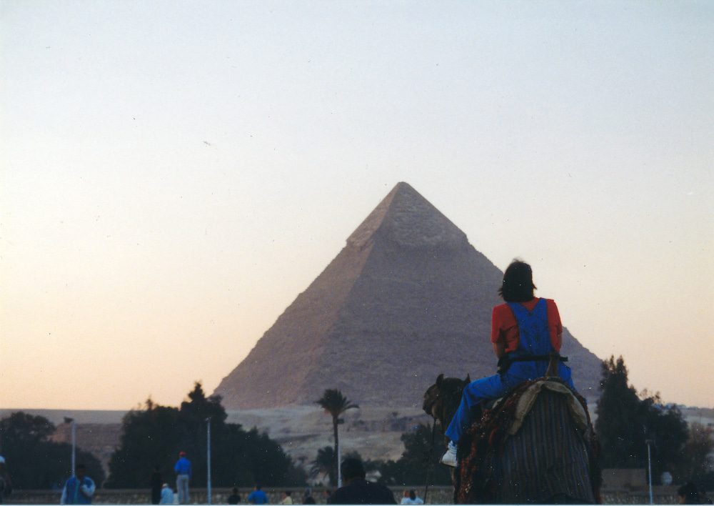 Maureen riding a camel in Egypt in front of a pyramid