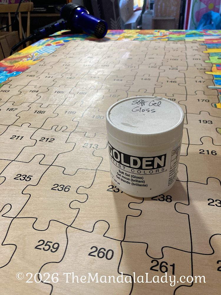 Golden Soft Gel Medium is applied to the wood panel and the puzzle pieces. The shiny area is where I’ve added the gel.